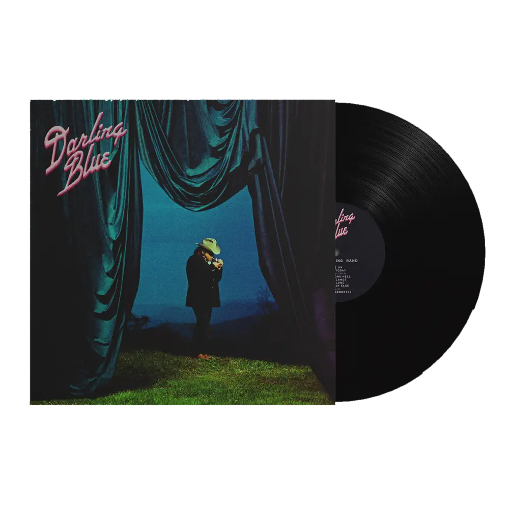 Black vinyl record with pink text on the label, housed in a sleeve featuring an image of a person standing under teal curtains against a blue backdrop.