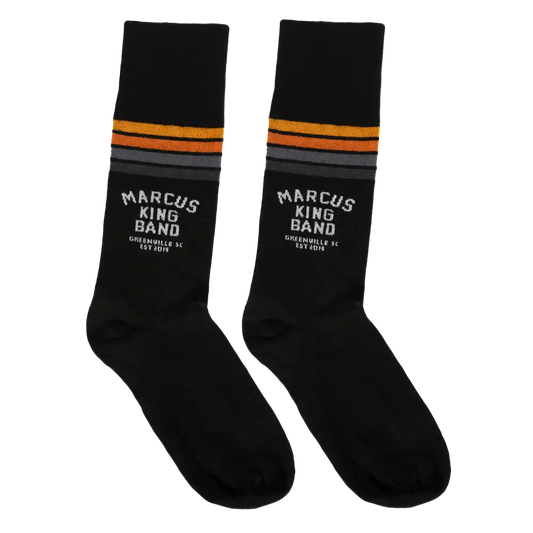 Black socks with orange and gray stripes near the top, featuring white ’marcus king band’ text and ’greensville sc est 2019’’ below.