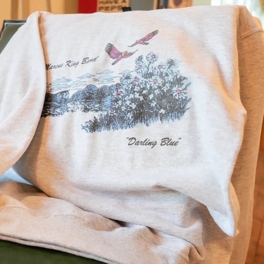 Heather gray sweatshirt featuring a colorful graphic of birds and flowers with the text ’marcus king band’ and ’’darling blue’’.