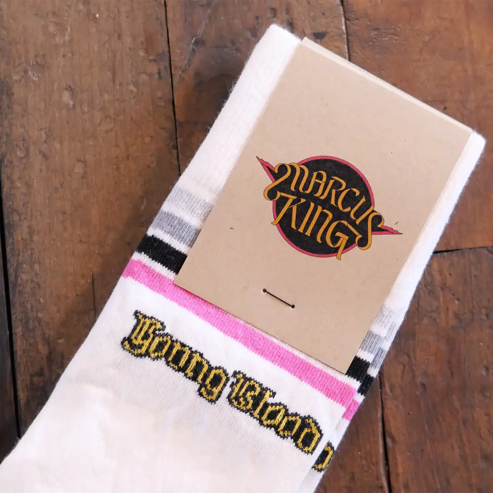 White socks with pink and black stripes, featuring embroidered ’young blood’ text in gold thread.